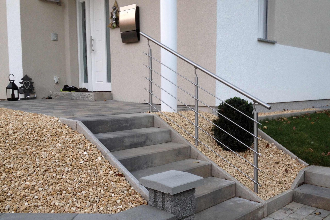 Escalier extérieur en béton avec rampe en acier inoxydable devant une maison