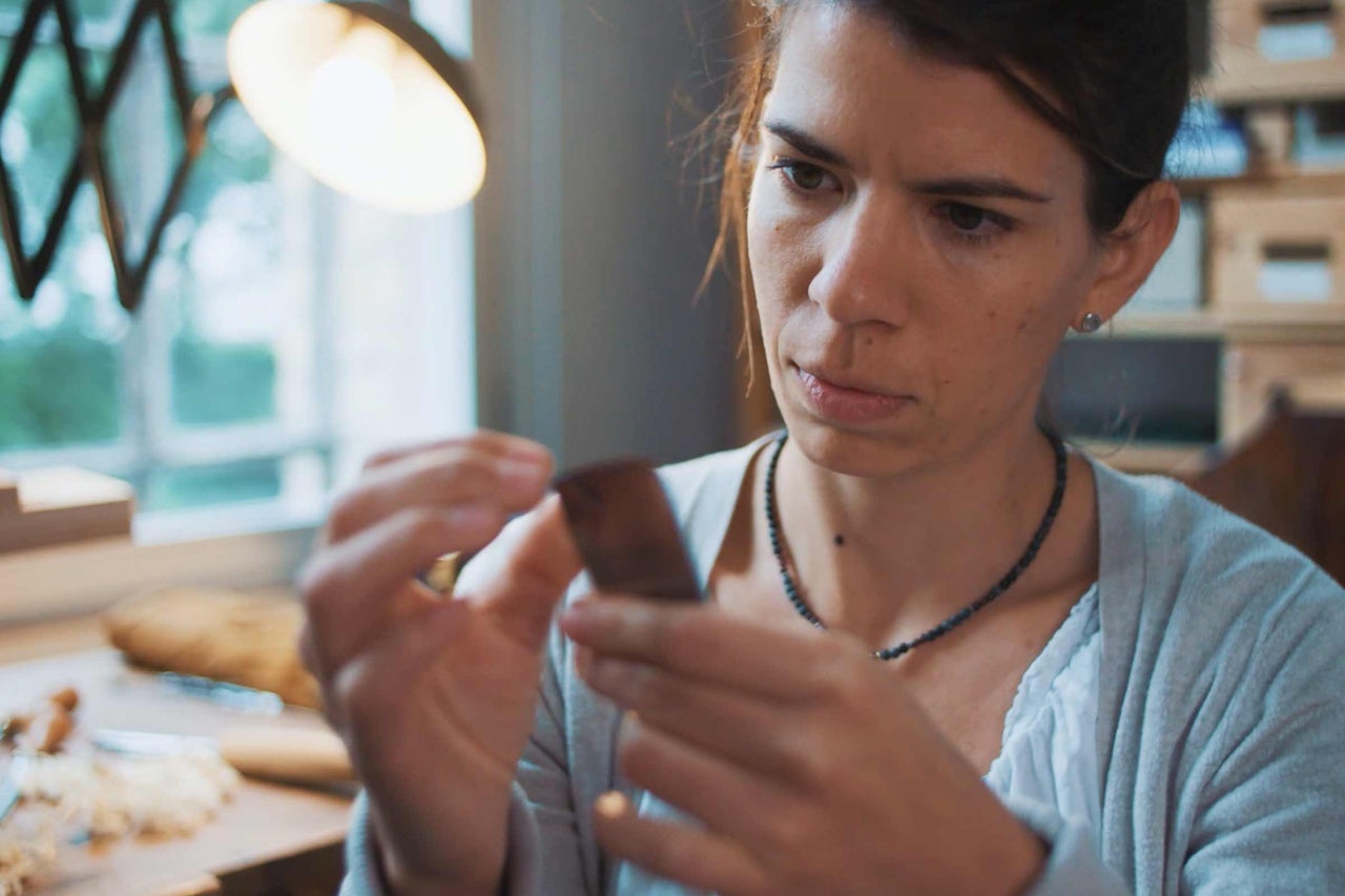 Frau prüft ein Holzstück in einer Werkstatt