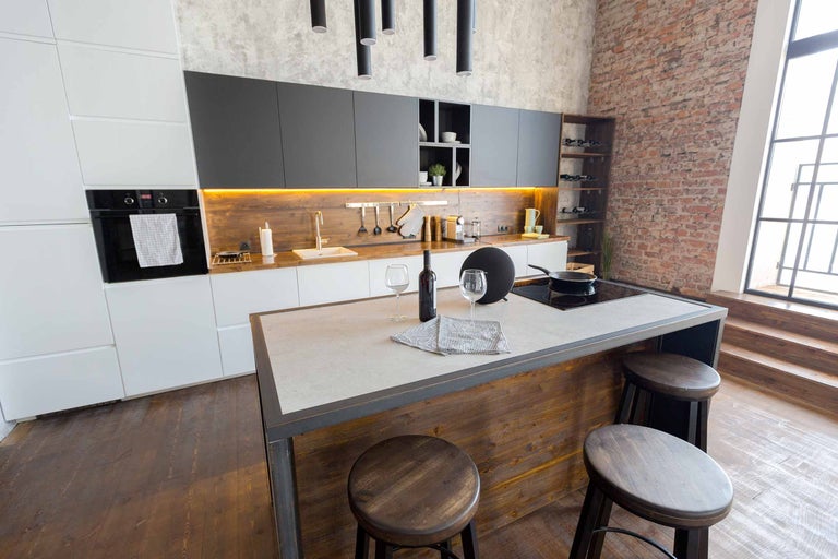 Cuisine moderne avec îlot de cuisine, tabourets de bar et appareils électroménagers.