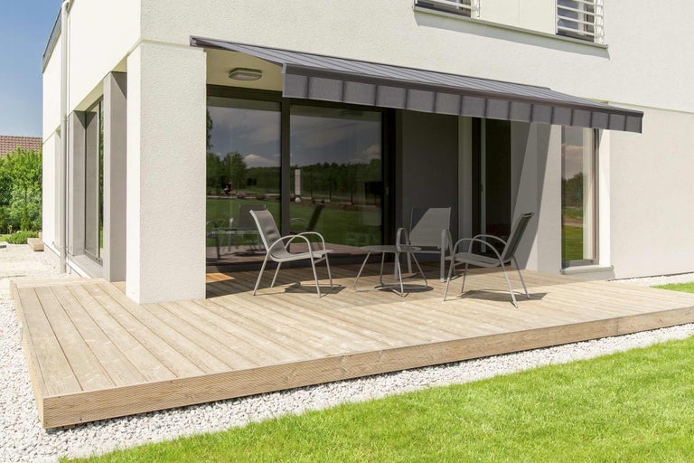 Terrasse mit Markise, Gartenmöbeln und Holzboden vor einem Wohnhaus