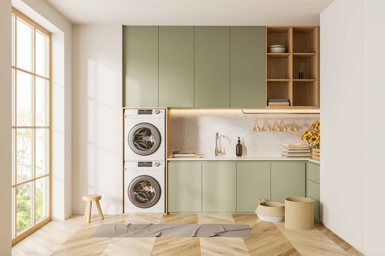 Buanderie lumineuse avec machine à laver, sèche-linge, armoires et plancher en bois