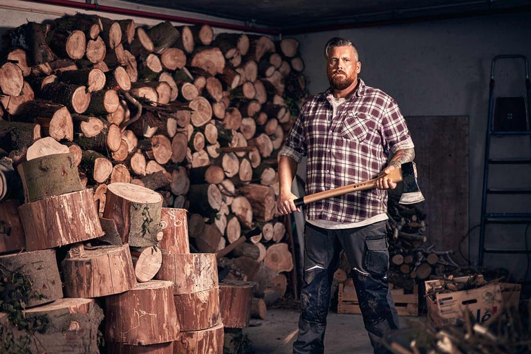 Homme avec une hache devant une pile de bois