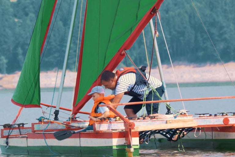 Homme et enfant avec gilets de sauvetage sur voilier.