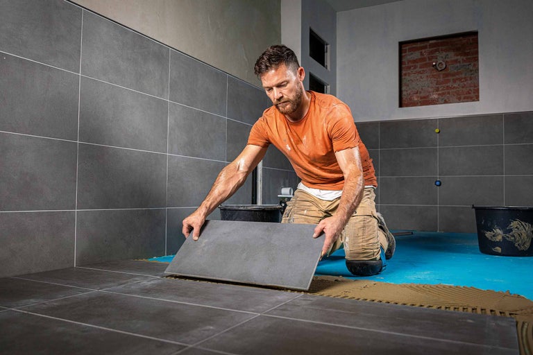 Fliesenleger verlegt Fliesen im Badezimmer.