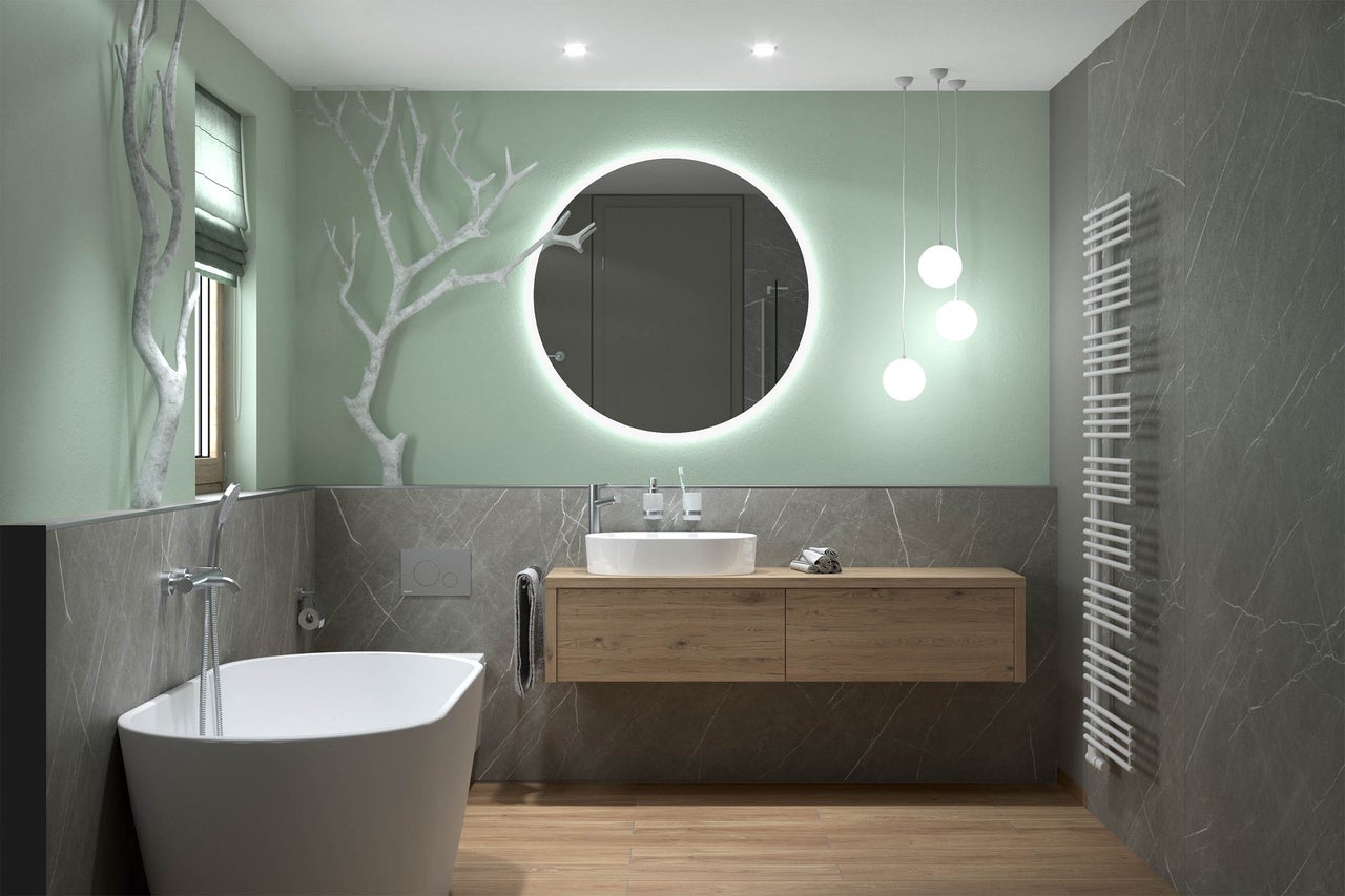 Salle de bains moderne avec baignoire en îlot, meuble sous-vasque en bois, miroir LED rond et grands carreaux effet marbre.