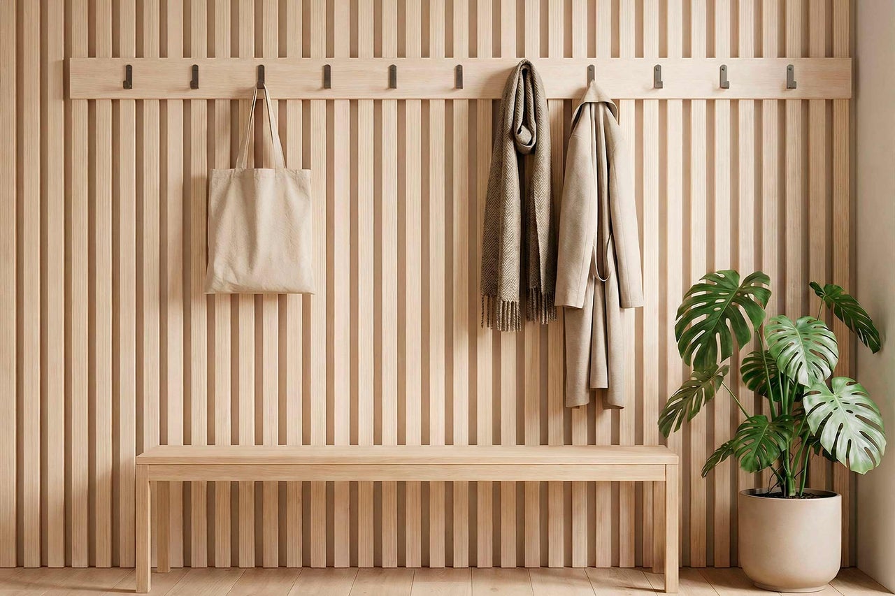 Entrée avec mur en panneaux de bois, banc de vestiaire, patère, sac, écharpe, manteau et plante en pot