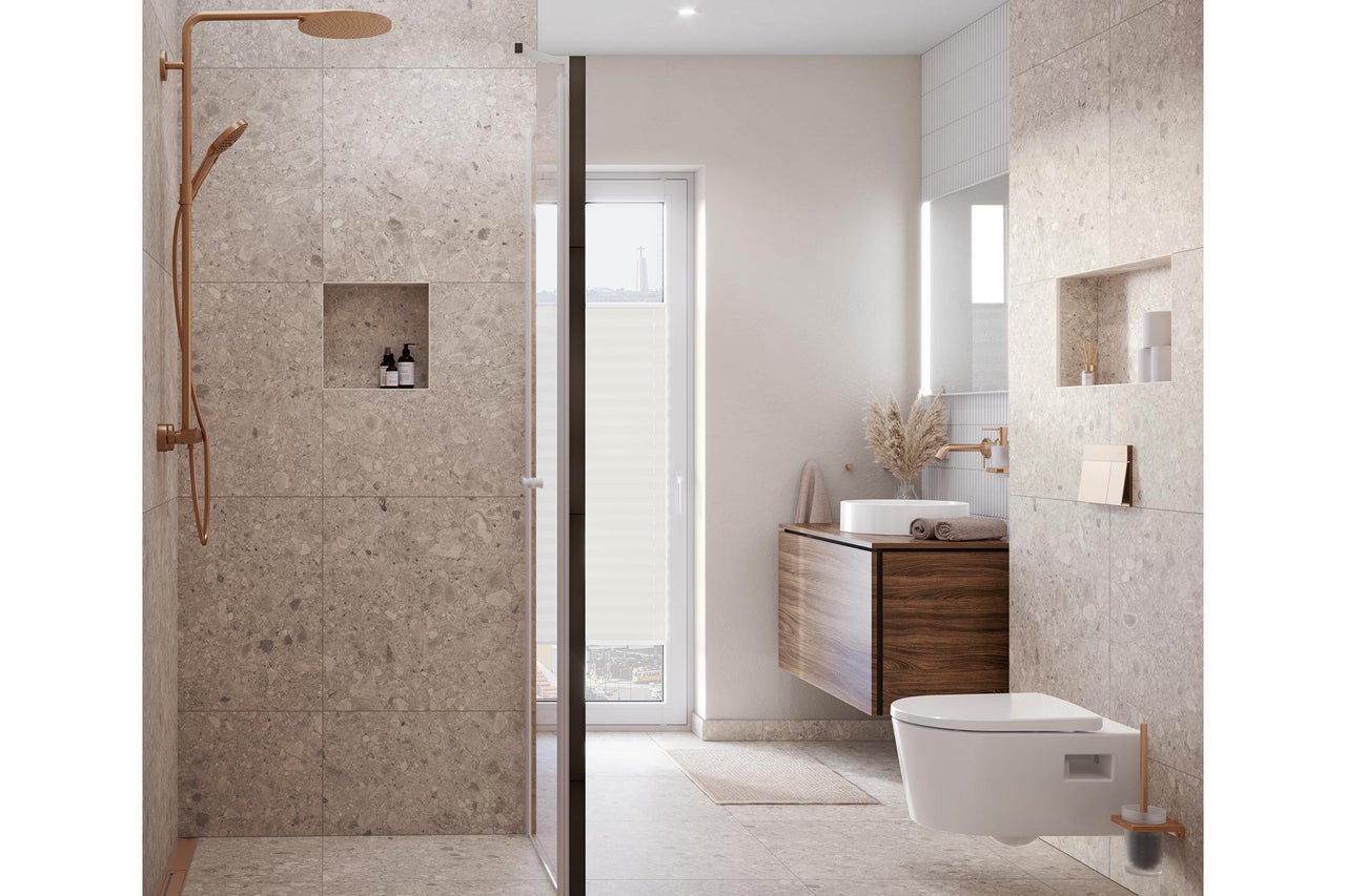 Salle de bains moderne avec grands carreaux aspect pierre naturelle, douche à l'italienne avec robinetterie cuivrée, meuble vasque et WC suspendu.