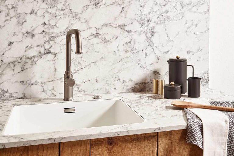 Küchenspüle mit Armatur und Küchenutensilien auf einer Arbeitsplatte aus Marmor