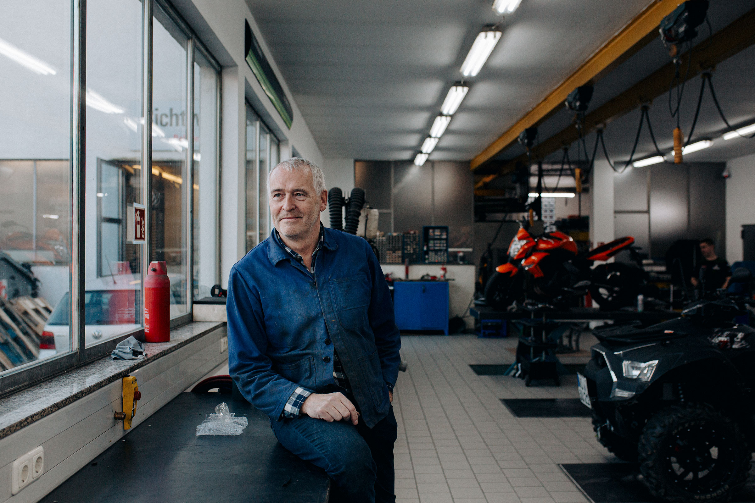 Werkstatt mit Mechaniker, Motorrädern und Arbeitsbereich