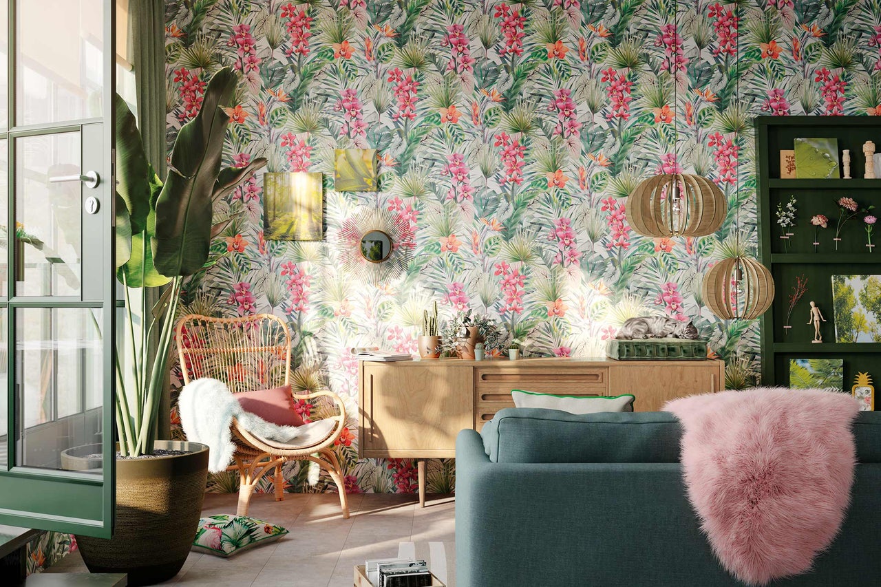 Wohnzimmer mit gemusterter Tapete, Rattansessel und Holzkommode