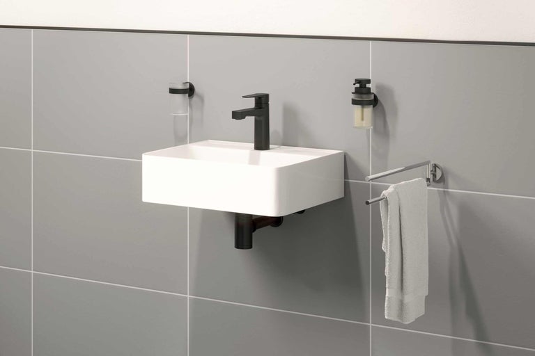 Vasque avec robinet, distributeur de savon, gobelet à brosse à dents et porte-serviettes sur mur gris