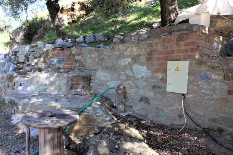 Aussenbereich mit Steinmauer, Stromkasten und Holzspule