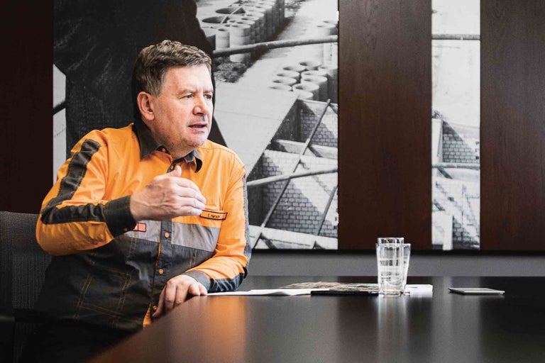 Un homme en vêtements de travail est assis à une table de conférence.