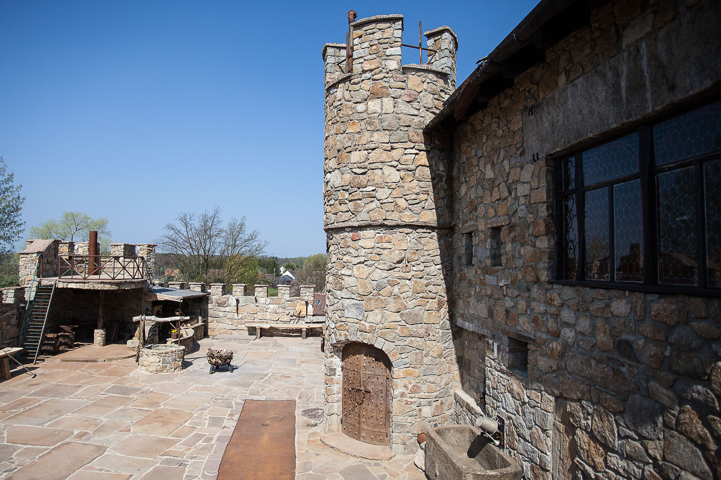 Außenansicht eines Hauses im Burgstil mit Steinturm und Steinhof