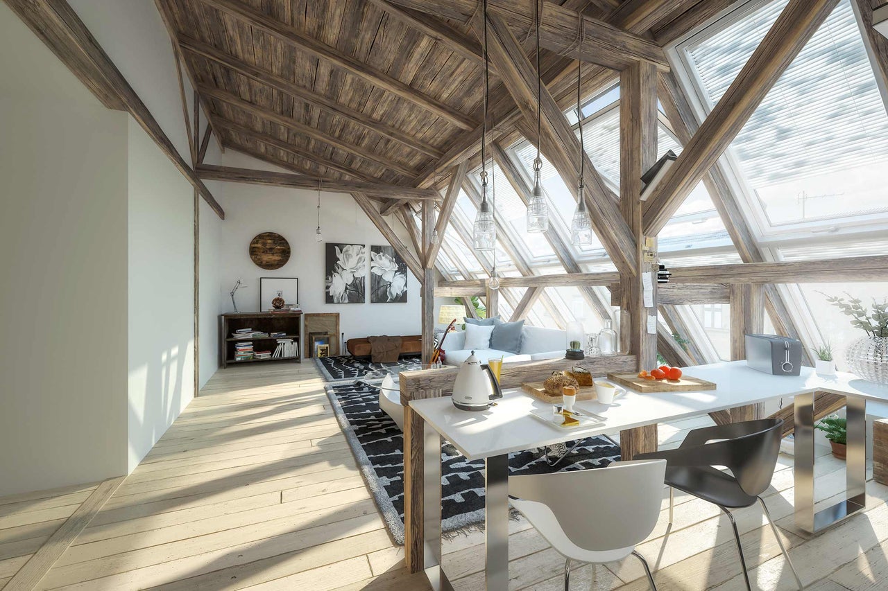 Pièce mansardée lumineuse avec poutres en bois, fenêtres de toit, table à manger et coin salon