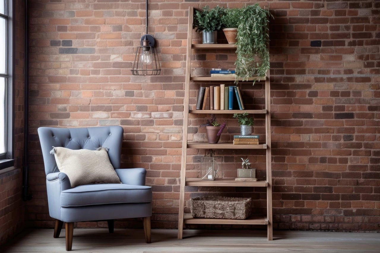 Salon avec fauteuil, bibliothèque et éléments décoratifs devant un mur en briques.