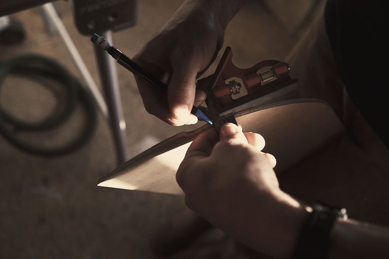 Une personne marque une planche de bois avec un crayon et une équerre.