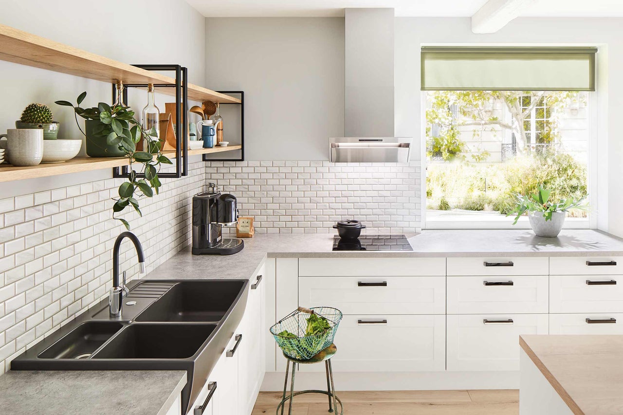 Cuisine claire avec évier, plaque de cuisson, hotte aspirante, carrelage et étagères