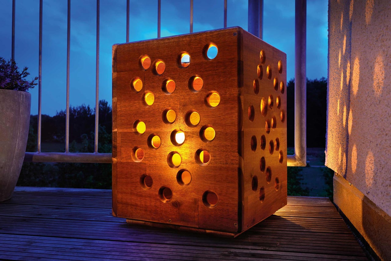 Lanterne carrée en bois avec ouvertures rondes pour l'extérieur.
