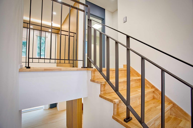 Escalier en bois avec rampe en métal dans une maison lumineuse.