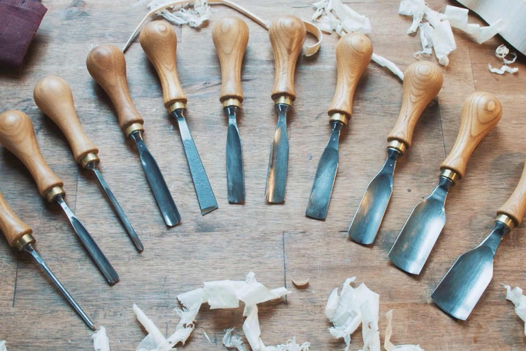 Eine Sammlung von Stecheisen mit Holzgriffen auf einer Holzoberfläche.