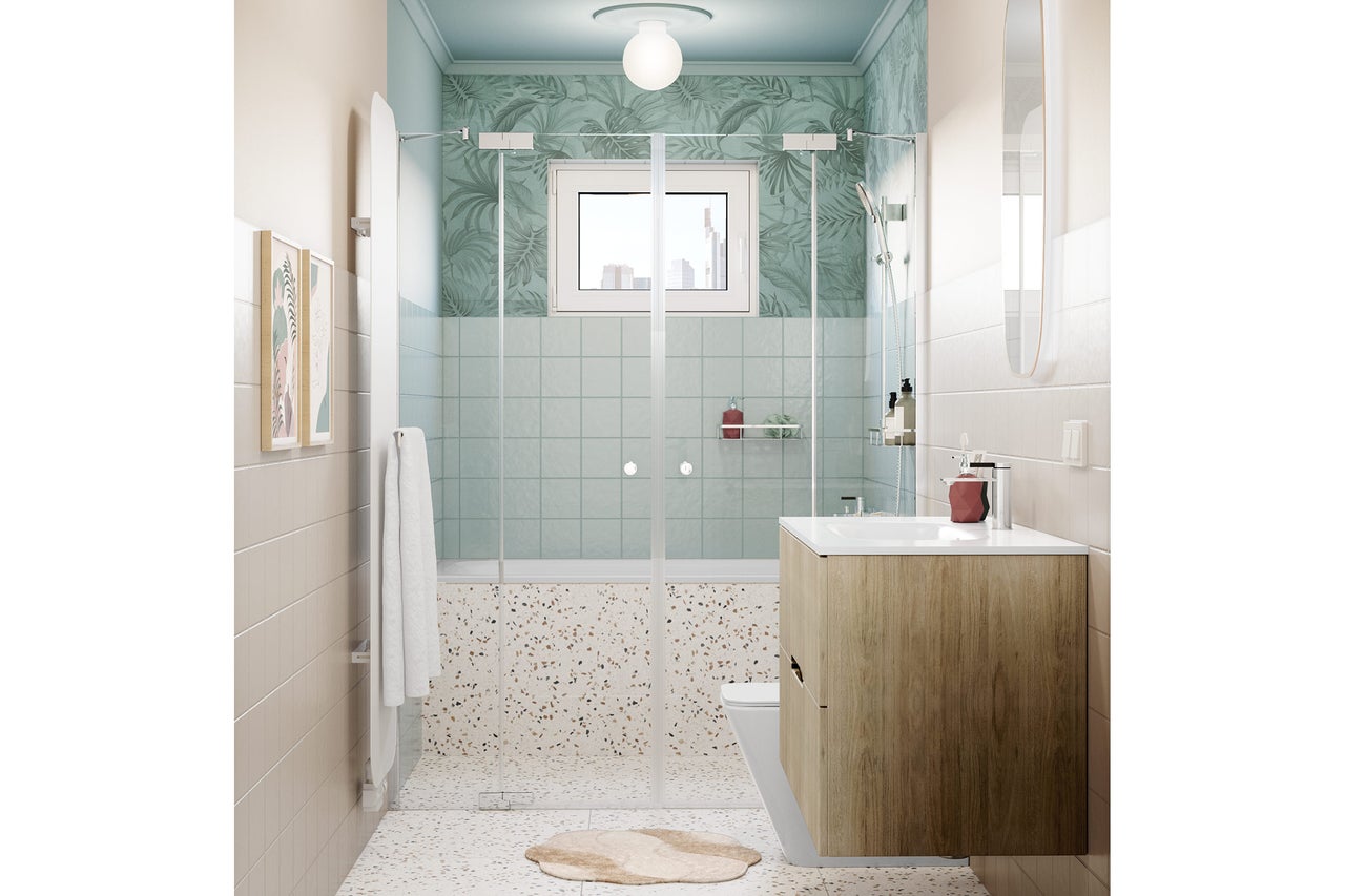 Salle de bains moderne avec meuble sous-lavabo en bois, paroi de douche en verre, sol en terrazzo et papier peint vert à motif de feuilles.