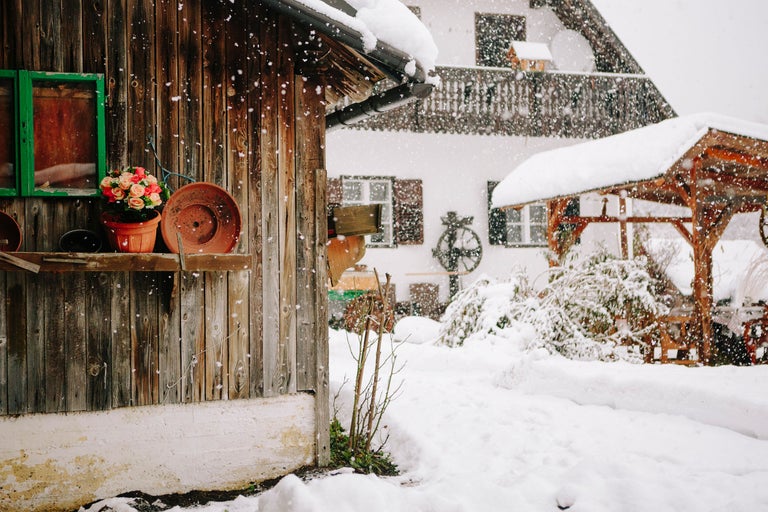 Winterliche Szene mit Haus, Gartenlaube und Schneefall