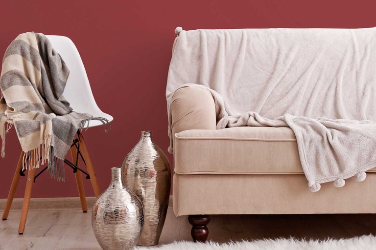 Dekoratives Wohnambiente mit Sofa, Stuhl, Decken und Vasen