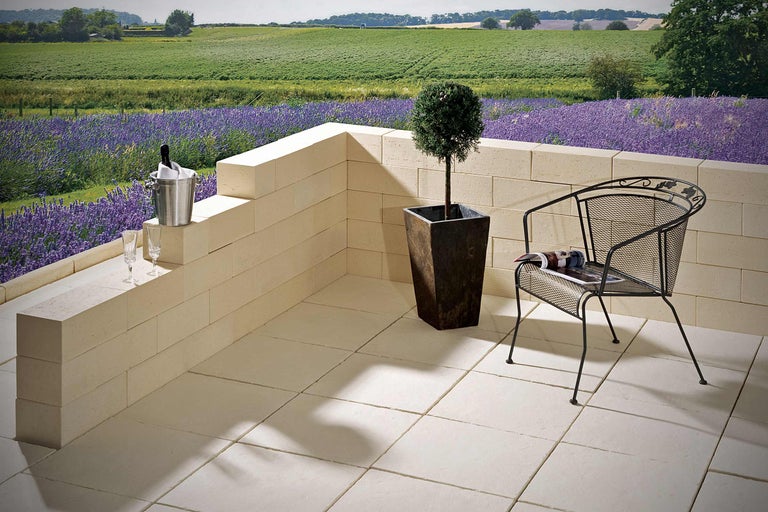 Terrasse mit Steinplatten, Mauer, Pflanze im Topf und Gartenstuhl