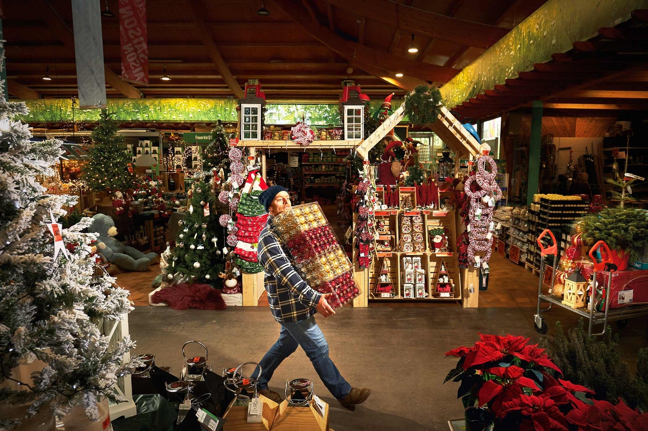 Un homme porte des boules de Noël dans le magasin Hornbach avec des décorations de Noël.