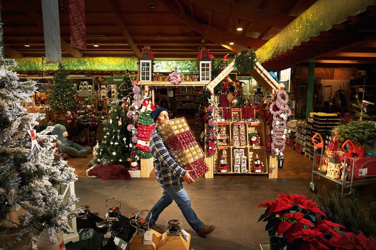 Un homme porte des boules de Noël dans le magasin Hornbach avec des décorations de Noël.