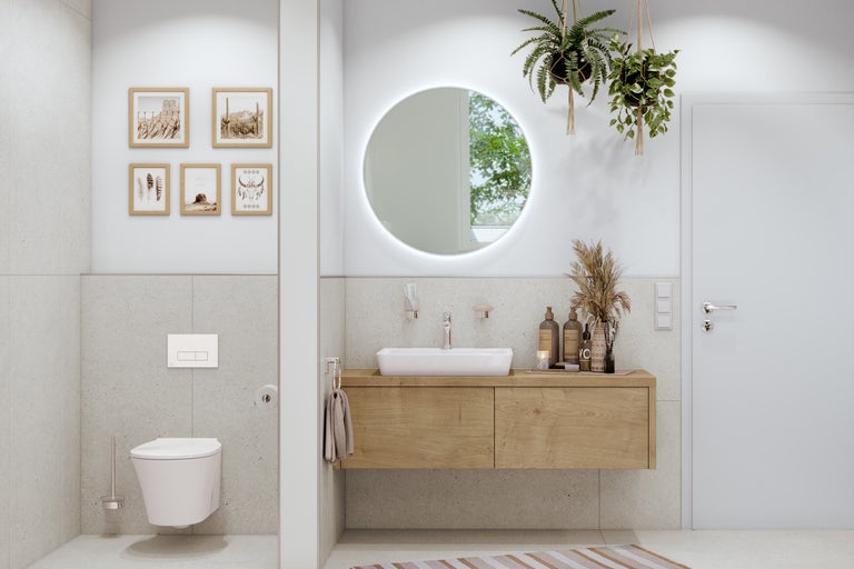 Helles Badezimmer mit Waschtischunterschrank, Toilette und runden Spiegel