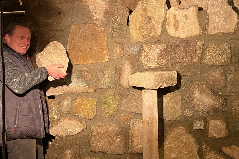 Mann hält Stein vor einer Wand aus Steinen