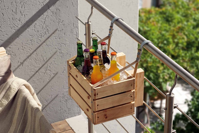 Caisse à boissons en bois remplie de bouteilles de boissons suspendue à une balustrade