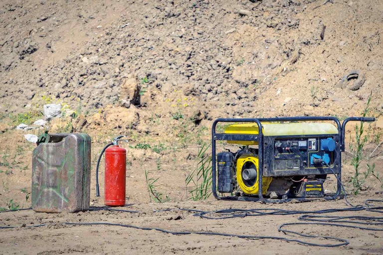 Stromgenerator mit Benzinkanister und Feuerlöscher im Freien