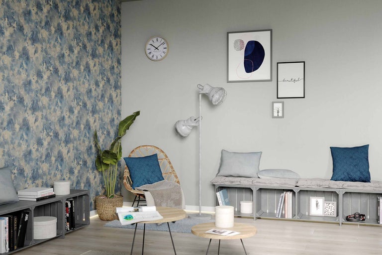 Wohnzimmer mit Rattansessel, Stehlampe, Couchtisch und Wandbildern