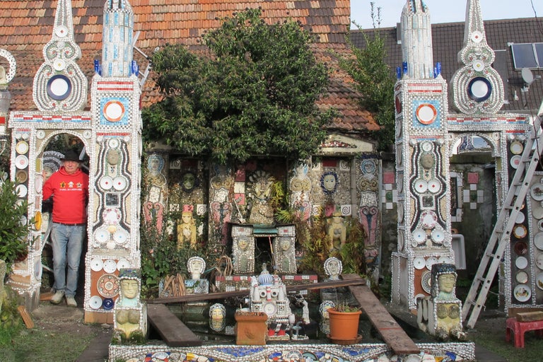 Außenansicht eines mit Keramik und Geschirr verzierten Hauses mit einem Mann im Eingang