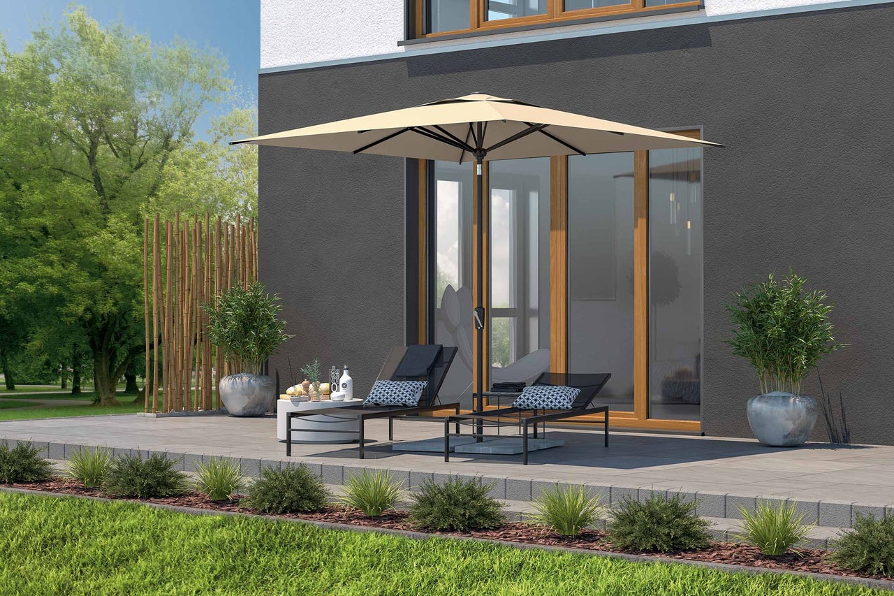 Terrasse avec parasol, chaises longues et table d'appoint devant une maison
