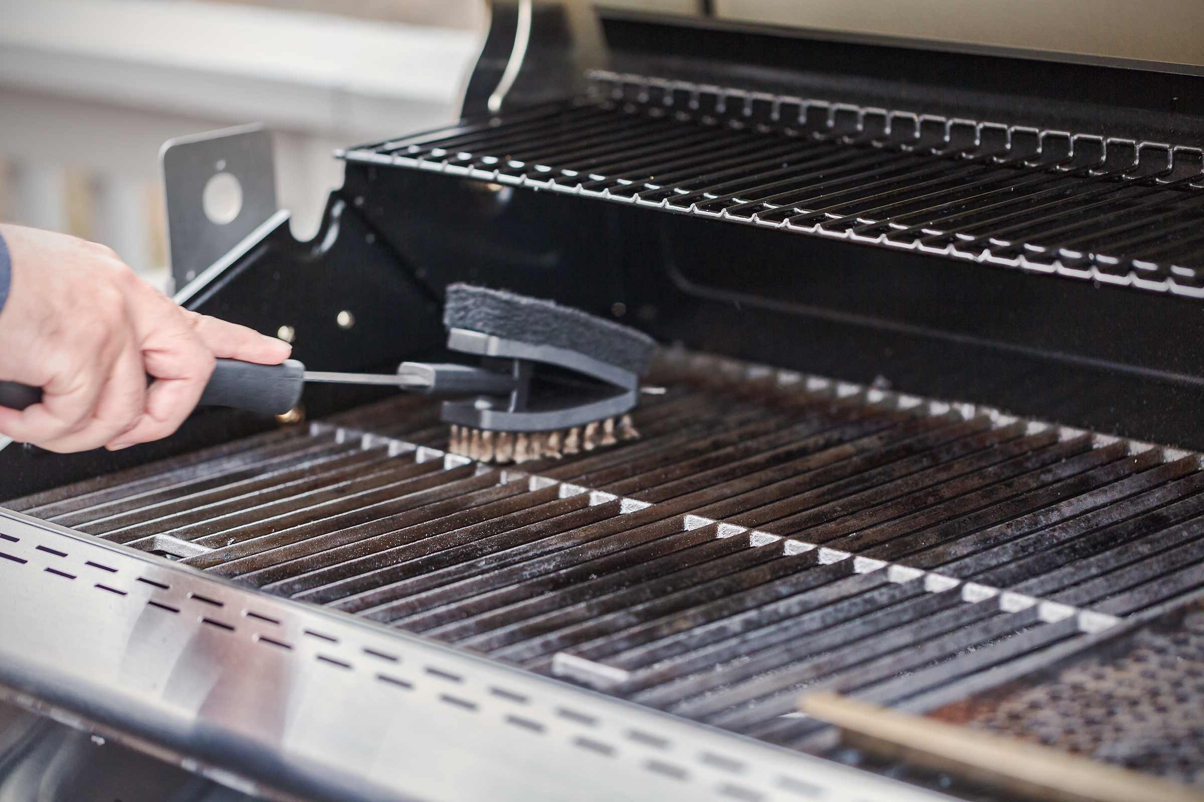 Une brosse à barbecue nettoie une grille de barbecue.