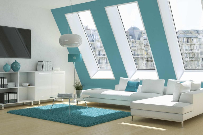 Salon lumineux avec fenêtres de toit, canapé, tapis et meubles blancs pour un intérieur moderne.