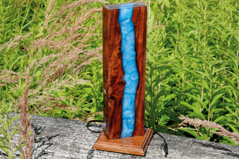 Lampe de table décorative en bois et résine synthétique devant des plantes