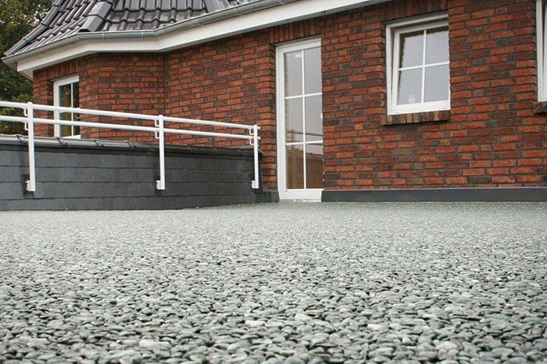 Terrasse de toit avec gravier et garde-corps devant un bâtiment en briques
