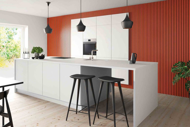 Cuisine claire avec îlot de cuisson, tabourets de bar et accents colorés sur le mur