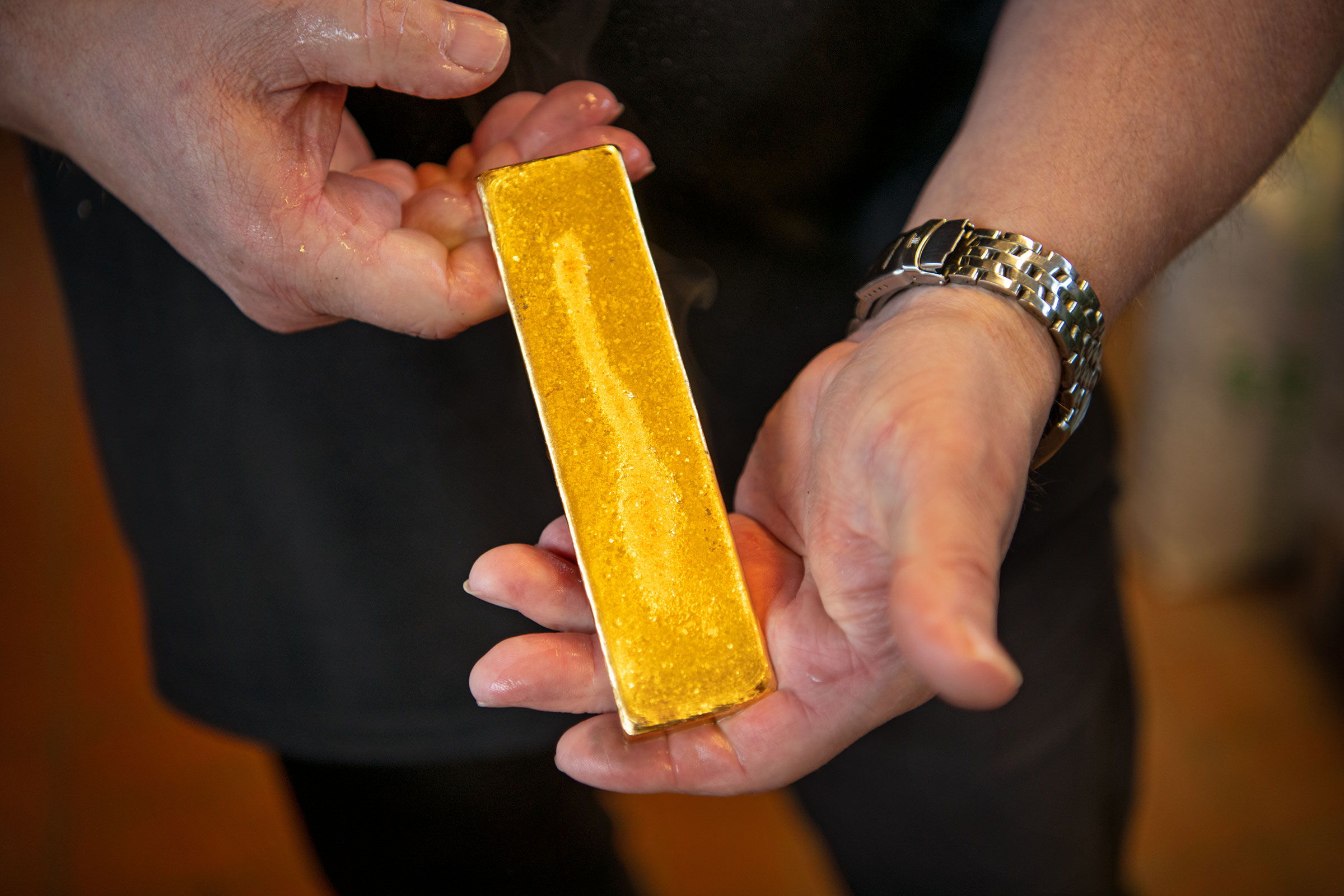 Eine Person hält einen goldenen Barren in den Händen.