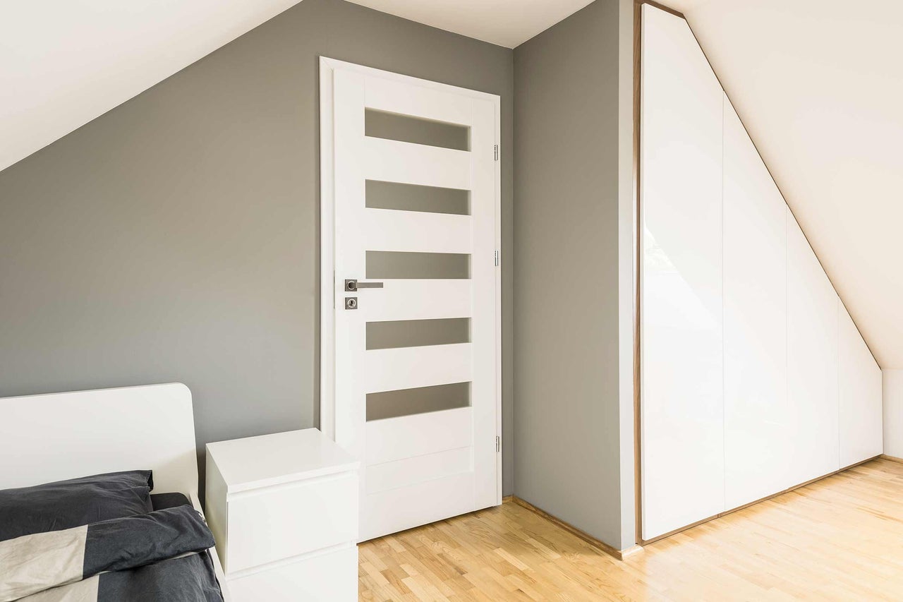 Chambre moderne avec porte blanche, armoire intégrée et lit