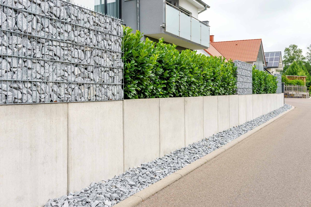 Mur de gabions combiné à des éléments en béton et des plantes vertes comme brise-vue dans le jardin