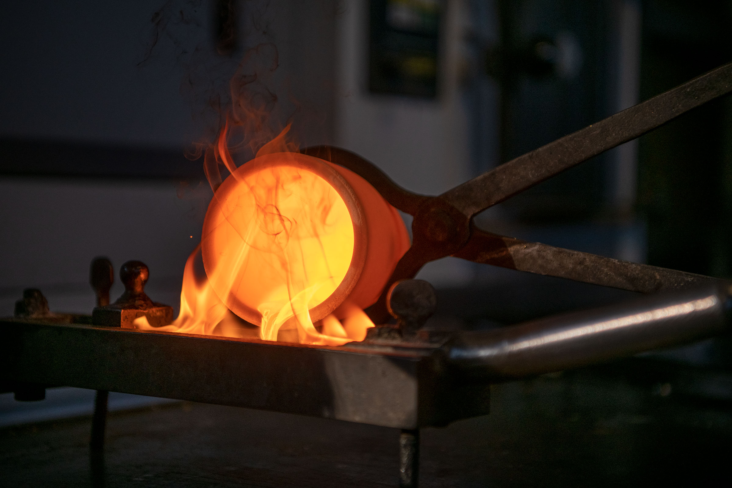 Schmelztiegel mit Zange in Flammen