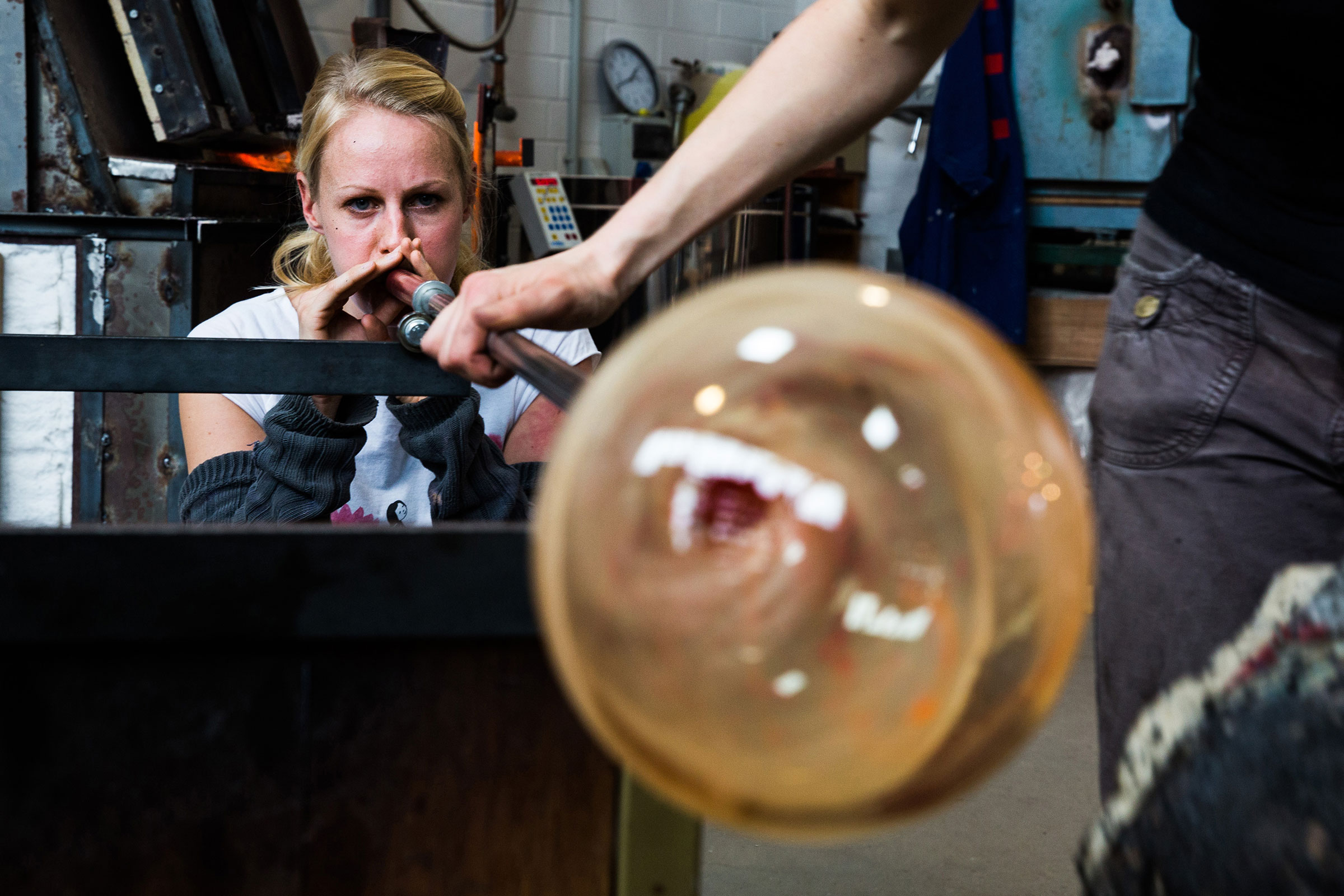 Glasbléiserin formt Glas mat enger Blasform an engem Atelier