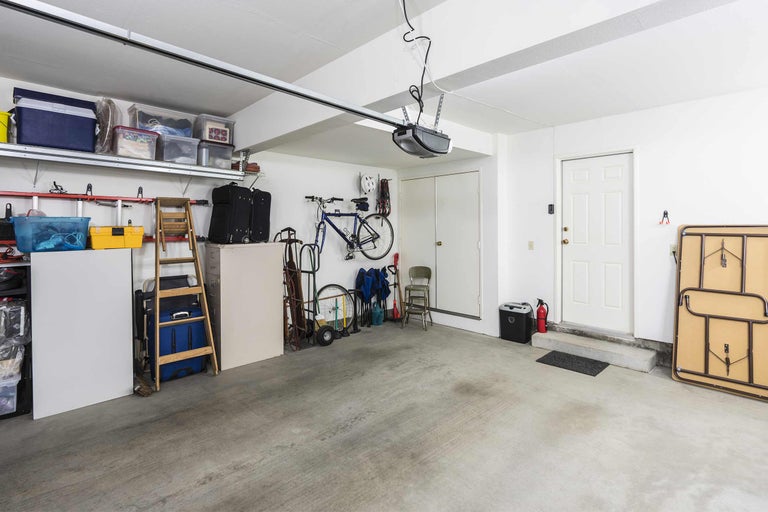 Garage bien rangée avec étagères, boîtes de rangement, vélos et ouvre-porte de garage