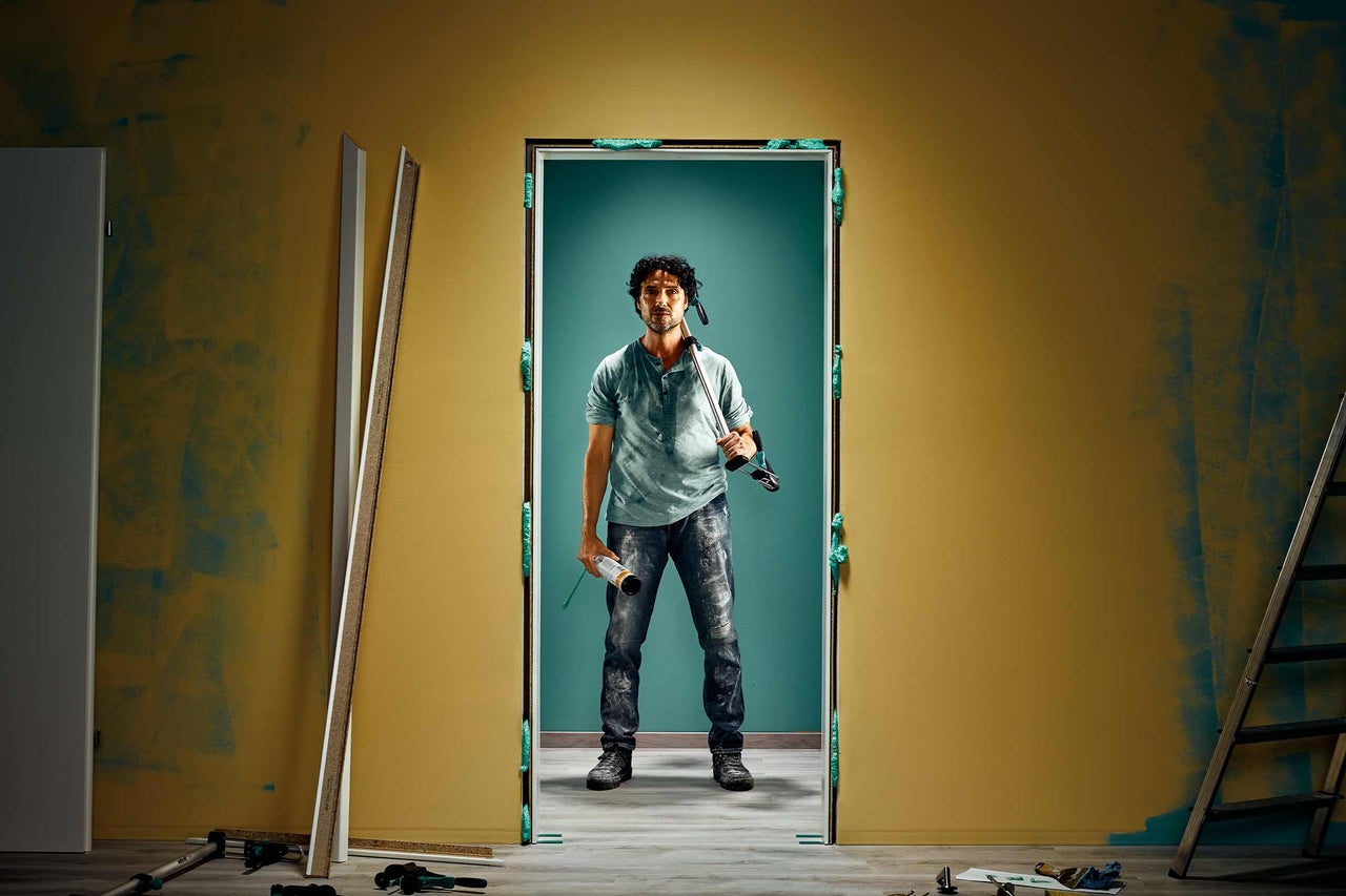 Un artisan installe un cadre de porte avec de la mousse expansive dans une pièce à rénover